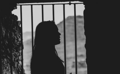The shadow of a woman with long hair behind bars.