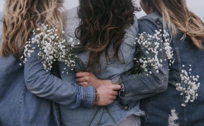 Three survivors embracing each other while holding white flowers in their hands